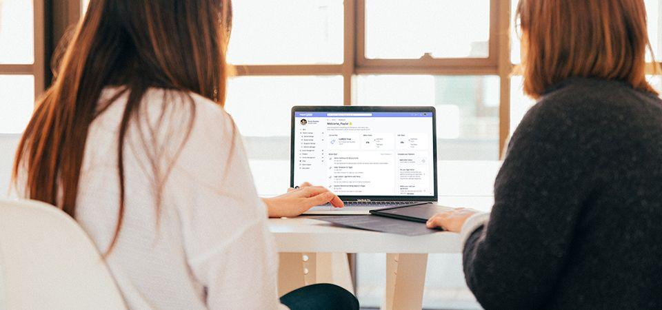 Two women sitting staring at laptop as they configure their new LoftOS Platform easily with this guide.